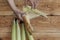 Young female cleaning freshly picked raw corns from cobs on wooden background. Process of Shucking corn