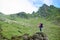 Young female climber admiring beauty of green rocky mountains and meadows and walking sheep in Romania