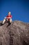 Young female climber atop a natural boulder outdoors