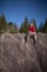 Young female climber atop a natural boulder outdoors