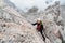 Young female climber on a steep and exposed rock face climbing a Via Ferrata