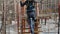 Young female climber walks by pendant log bridge on high ropes course in extreme park