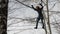 Young female climber walks by pendant rope bridge on high ropes course in extreme park. Rock climbing concept