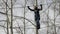 Young female climber walks by pendant rope bridge on high ropes course in extreme park. Rock climbing concept