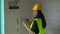 Young female construction worker or engineer, wearing high visibility green vest and yellow helmet going through checklist pad