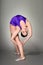 Young female contortionist performs, on dark background