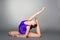 Young female contortionist in purple leotard on dark background