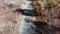 Young female cyclist riding on road bike at autumn forest, aerial drone view. Rear follow view of woman cycling on bicycle in autu