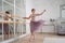 A young female dancer is engaged in ballet practice at a ballet machine,