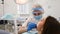 Young female dentist curing tooth cavity and talking to patient with caries.