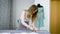 Young female designer with tape-line on her neck standing in dressmaking studio and drawing lines with chalk and rule