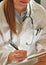 Young female doctor making notices on a clipboard