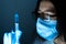 Young female doctor in a medical mask and gloves holds a syringe with a coronavirus vaccine and a vaccine chip inside. Conspiracy