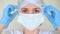 Young female doctor or nurse puts on a medical protective mask on a white background. Coronavirus, epidemic, pandemic