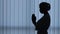 Young female doctor in protective mask - silhouette praying and hoping gesture