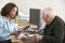 Young female Doctor taking senior man\'s blood pressure