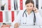 Young female doctor talking on phone at her desk in office.