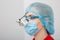 Young female Doctor wearing dental loupe binoculars, headshot portrait at work process