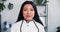 Young female doctor at work. Portrait of beautiful multiethnic medic woman in lab coat smile at camera at light office.