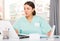 Young female doctor working at laptop in her office