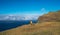 Young female dressed in orange waterproof jacket walking by the mountain above the cloud route on Madeira island, Ponta do Pargo,