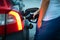 Young female driver refueling her car at night with gas