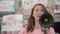 Young female eco-activist yelling through megaphone with crowd of people at the background. Group of dissatisfied