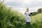 Young female ecologist scientist in goggles standing in green field and working on glass transparent screen