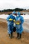 Young female ecologists in protective workwear standing on polluted soil or clay