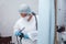 A young female endoscopist in a white protective suit, cap and gloves prepares the equipment for work.