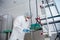 A young female endoscopist in a white protective suit, cap and gloves prepares the equipment for work.