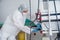 A young female endoscopist in a white protective suit, cap and gloves prepares the equipment for work.