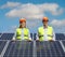 Young female engineer and mature male engineer posing between solar panels