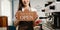 Young female entrepreneur hanging a welcome sign in front of a coffee shop. Beautiful waitress or hostess holding a tablet