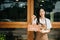 Young female entrepreneur hanging a welcome sign in front of a coffee shop. Beautiful waitress or hostess holding a tablet