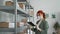 young female entrepreneur wearing medical mask and gloves inspects packaged goods on warehouse shelves to be sent to