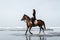 young female equestrian riding horse with ocean