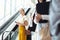 Young female executive taking escalator while Caucasian female executive look straight ahead