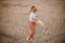 Young female exploring sandy beach with hat. Hipster girl, young traveler in nature desert. A woman walks in the desert