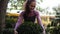 Young female florist in apron embracing green boxwood in the greenhouse. Happy woman in the greenhouse loves buxus and