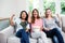 Young female friends cheering while sitting on sofa