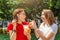 Young female friends laugh and eat yoghurt outdoors