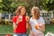 Young female friends laugh and eat yoghurt outdoors