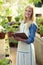 Young female gardener examining potted plants