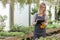 A young female gardener keeps a record of flowers in a greenhouse