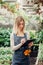 A young female gardener keeps a record of flowers in a greenhouse