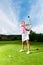 Young female golf player on course doing golf swing