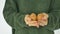 Young female in green sweater is showing eggs with hand drawn face with a smile from straw basket, easter preparation