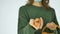 Young female in green sweater is showing hand drawn eggs with anthropomorphic smiley face from straw basket, easter