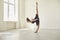 Young female gymnast doing vertical standing split balance during rehearsal in modern gym or studio